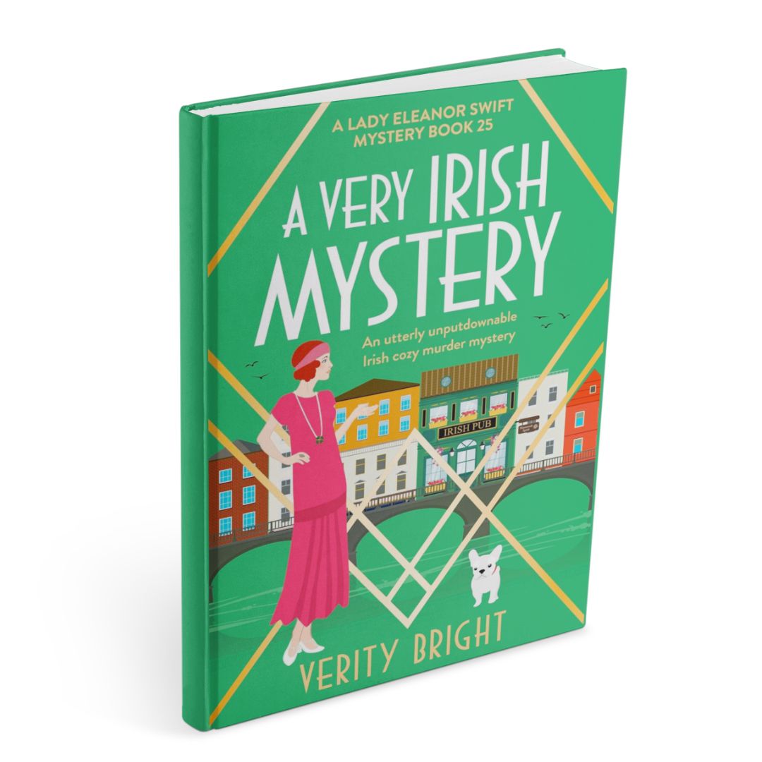 Cover of A Very Irish Mystery by Verity Bright, Lady Eleanor Swift Mysteries Book 25, showing a woman in a pink dress beside an Irish riverside street with colourful buildings, an Irish pub, a bridge, and a small white dog.