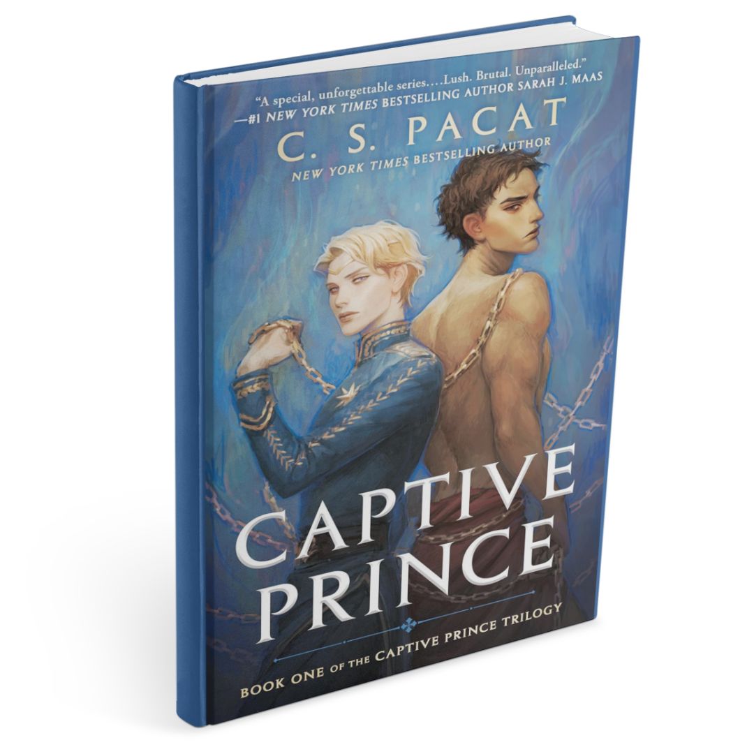 Illustrated hardcover of Captive Prince by C.S. Pacat, a dark fantasy romance, showing Prince Laurent, pale and blond in ornate blue court dress, standing back to back with Damianos (Damen), dark-haired and bare-backed, the two bound by chains against a moody blue background.