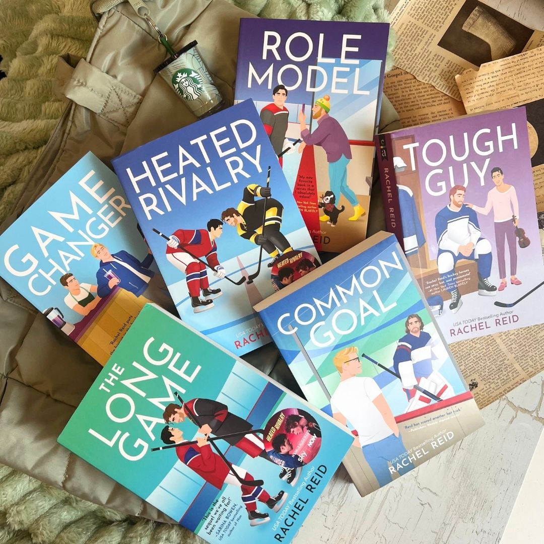 Flat lay of Rachel Reid’s Game Changers hockey romance paperbacks, including Heated Rivalry, The Long Game, Role Model, Tough Guy, Common Goal, and Game Changer, arranged with a Starbucks cup, jacket, and bookish background.
